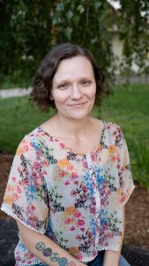Woman with short curly hair in floral top.