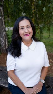 Woman in white blouse sitting on bench.