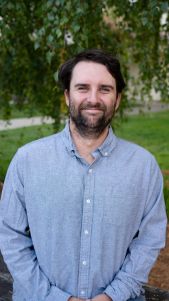 Man with beard smiling in casual attire.