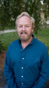 Bearded man wearing a blue shirt outdoors.